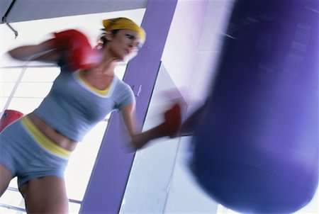 punching bag - Woman Wearing Boxing Gloves Punching Heavy Bag Stock Photo - Rights-Managed, Code: 700-00063105