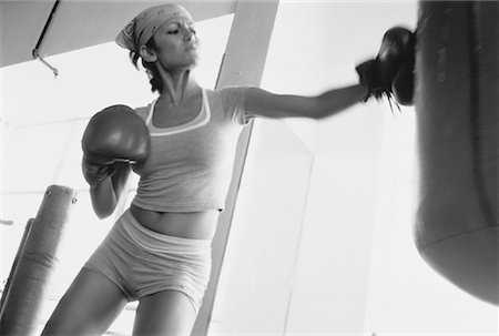 Woman Wearing Boxing Gloves Punching Heavy Bag Stock Photo - Rights-Managed, Code: 700-00063106