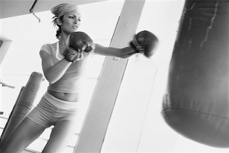punching bag - Woman Wearing Boxing Gloves Punching Heavy Bag Stock Photo - Rights-Managed, Code: 700-00063107