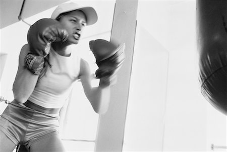 fitness black and white - Woman Wearing Boxing Gloves Punching Heavy Bag Foto de stock - Con derechos protegidos, Código: 700-00063108