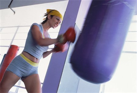 punching bag - Woman Wearing Boxing Gloves Punching Heavy Bag Stock Photo - Rights-Managed, Code: 700-00063823