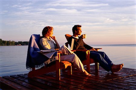 Couple Sitting in Chairs on Dock With Laptop, Newspaper and Mug Stock Photo - Rights-Managed, Code: 700-00074047
