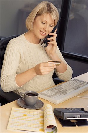 Businesswoman Sitting at Desk Using Phone, Holding Credit Card Stock Photo - Rights-Managed, Code: 700-00074082