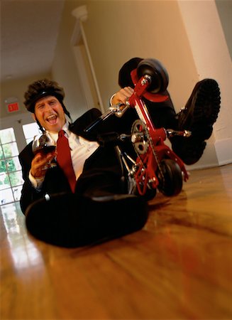 Businessman Lying on Floor with Mini Bike and Drink Stock Photo - Rights-Managed, Code: 700-00074668