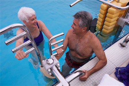 Mature Couple in Swimwear Exercising in Swimming Pool Foto de stock - Direito Controlado, Número: 700-00075428