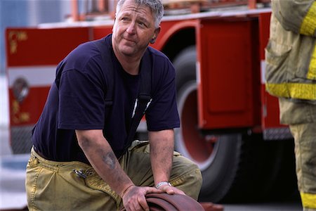 fuliggine - Male Firefighter Rolling Hose Fotografie stock - Rights-Managed, Codice: 700-00075537