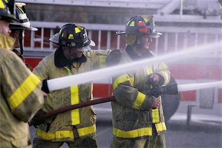 spraying water hose - Three Male Firefighters Spraying Water from Hoses Stock Photo - Rights-Managed, Code: 700-00075551