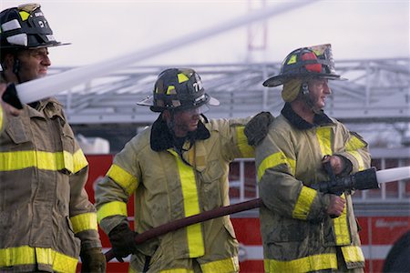 firefighters spray water - Pompiers mâles pulvériser de l'eau des tuyaux Photographie de stock - Rights-Managed, Code: 700-00076159