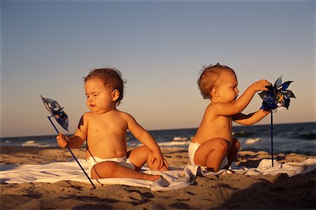 Two Babies Sitting on Beach with Pinwheels Foto de stock - Con derechos protegidos, Código: 700-00077020