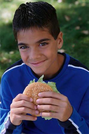 Portrait of Boy Eating Hamburger Outdoors Foto de stock - Con derechos protegidos, Código: 700-00077196