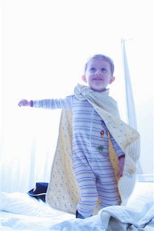 Boy Wearing Blanket as Cape Standing on Bed Stock Photo - Rights-Managed, Code: 700-00077317