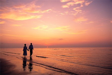 simsearch:700-00152780,k - Couple d'âge mûr marchant sur la plage main dans la main au coucher du soleil Photographie de stock - Rights-Managed, Code: 700-00077505