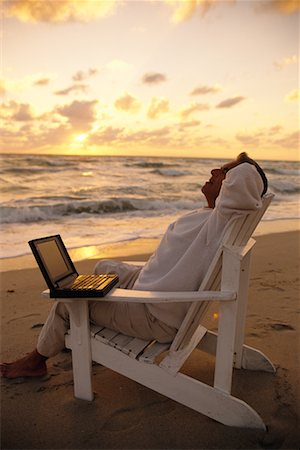 Mature Man Relaxing in Chair on Beach with Laptop Computer at Sunset Stock Photo - Rights-Managed, Code: 700-00077679