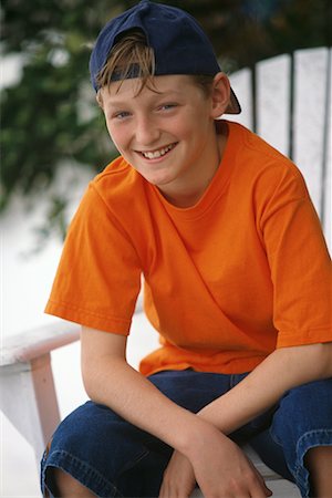 Young Man in Chair With Backwards Baseball Cap Stock Photo