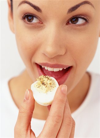 deviled egg - Woman Eating Deviled Egg Foto de stock - Con derechos protegidos, Código: 700-00078003