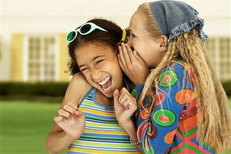 Girl Whispering into Friend's Ear Outdoors Stock Photo - Rights-Managed, Code: 700-00078109