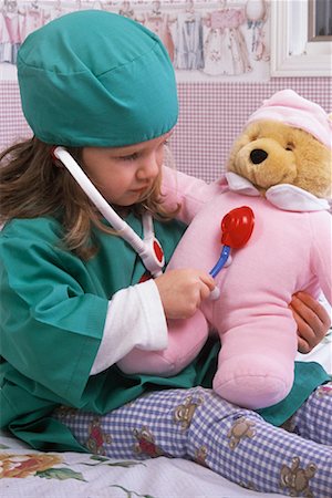 Girl Sitting on Bed in Doctor Costume, Playing Doctor with Teddy Bear Stock Photo - Rights-Managed, Code: 700-00079044