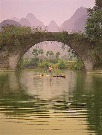 Man in Raft on Yulong River near Dragon Bridge, near Yangshuo Guangxi Region, China Foto de stock - Direito Controlado, Número: 700-00079850