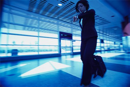 simsearch:700-00071171,k - Businesswoman Checking Watch Pulling Luggage in Terminal Fotografie stock - Rights-Managed, Codice: 700-00071167