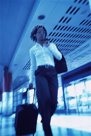 simsearch:700-00071171,k - Businesswoman Walking in Terminal Pulling Luggage Fotografie stock - Rights-Managed, Codice: 700-00071163