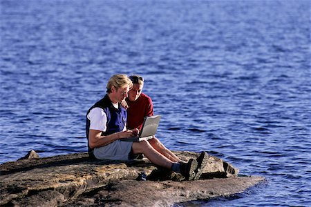 Couple Sitting on Rock in Lake Using Laptop Computer Haliburton, Ontario, Canada Stock Photo - Rights-Managed, Code: 700-00071227