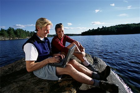Couple Sitting on Rock in Lake Using Laptop Computer Haliburton, Ontario, Canada Stock Photo - Rights-Managed, Code: 700-00071228