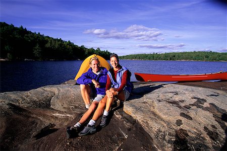 Porträt von paar sitzen auf den Felsen mit Zelt und Kanu in der Nähe von See, Haliburton, Ontario, Kanada Stockbilder - Lizenzpflichtiges, Bildnummer: 700-00071223