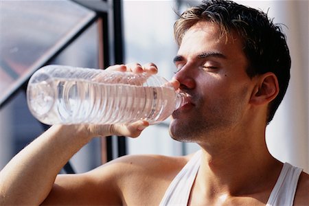 satisfied (thirst) - Man Standing near Window Drinking Bottle of Water Foto de stock - Con derechos protegidos, Código: 700-00072490