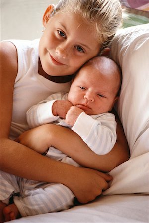 sister hugs baby - Portrait of Girl Sitting on Bed Holding Baby Stock Photo - Rights-Managed, Code: 700-00072526