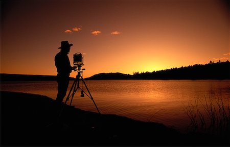 simsearch:700-00151974,k - Silhouette of Person Taking Photograph of Sunset over Lake And Trees Stock Photo - Rights-Managed, Code: 700-00073047