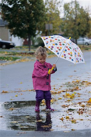 Girl Holding Umbrella, Playing in Puddle Ajax, Ontario, Canada Stock Photo - Rights-Managed, Code: 700-00073874