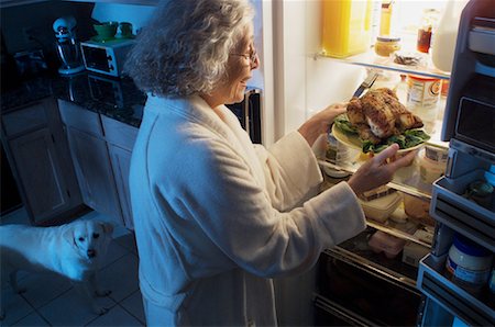 dogs and woman in kitchen - Mature Woman Standing at Fridge Having Chicken as Midnight Snack Stock Photo - Rights-Managed, Code: 700-00084274