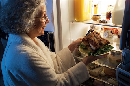 Mature Woman Standing at Fridge Having Chicken as Midnight Snack Stock Photo - Rights-Managed, Code: 700-00084275