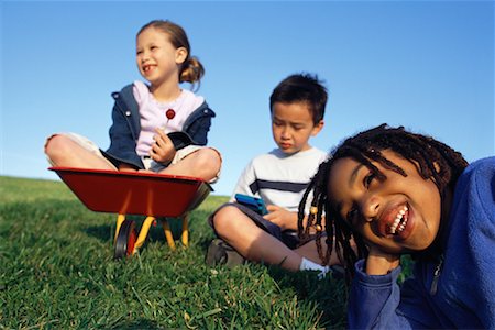 Trois enfants assis à l'extérieur avec le portable de jeu vidéo et plein air brouette Photographie de stock - Rights-Managed, Code: 700-00082231