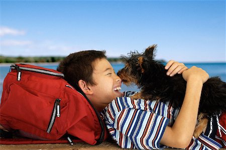 Boy Lying Outdoors with Dog Licking Face Stock Photo - Rights-Managed, Code: 700-00083943