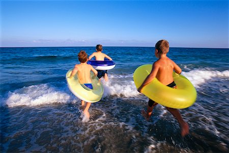 Children Running on Beach with Inner Tubes Stock Photo - Rights-Managed, Code: 700-00150968