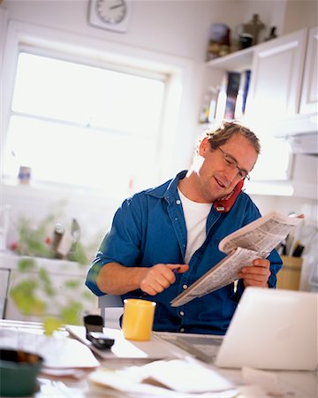 Man Reading Newspaper and Using Phone in Kitchen Stock Photo - Rights-Managed, Code: 700-00151551