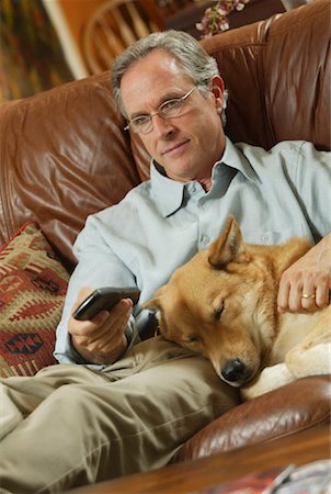 simsearch:700-01183739,k - Man Sitting on Sofa with Dog Holding Remote Control Stock Photo - Rights-Managed, Code: 700-00152689