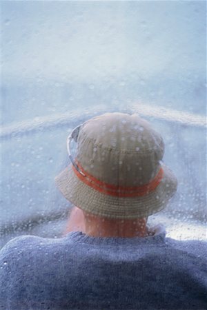 Homme assis sur un bateau pendant la pluie Photographie de stock - Rights-Managed, Code: 700-00167775