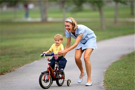 rodinha da bicicleta - Mother Helping Son Ride Bike Foto de stock - Direito Controlado, Número: 700-00160993