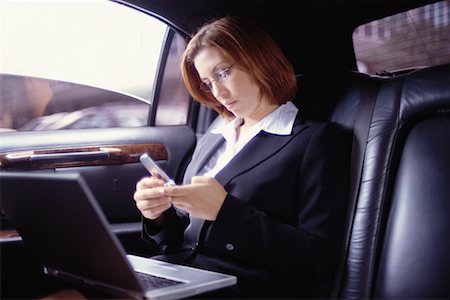 Woman Using Laptop and Phone In Limo Stock Photo - Rights-Managed, Code: 700-00195282