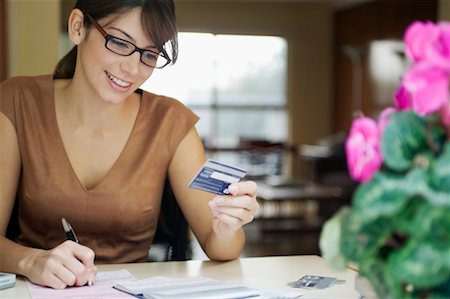 Woman Writing on Bill Holding Credit Card Stock Photo - Rights-Managed, Code: 700-00269276