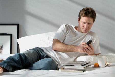 simsearch:700-00159009,k - Man Using Cell Phone on Bed Stock Photo - Rights-Managed, Code: 700-00328689