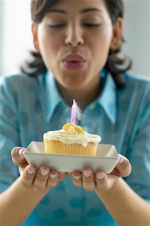 soplar velas - Woman Blowing Candle on Cupcake Foto de stock - Con derechos protegidos, Código: 700-00342916