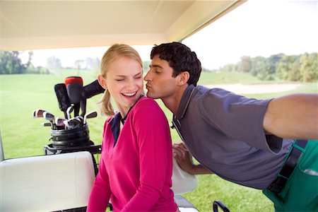 Man Leaning in to Kiss Woman in Golf Cart Stock Photo - Rights-Managed, Code: 700-00452973