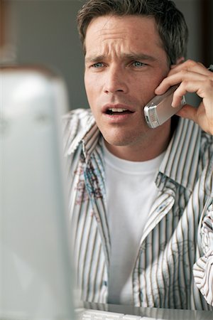 Man Looking at Computer Screen and Using Cellular Telephone Stock Photo - Rights-Managed, Code: 700-00524461