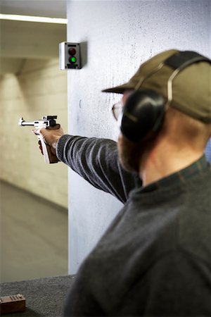 Tir d'une arme de poing dans le stand de tir de l'homme Photographie de stock - Rights-Managed, Code: 700-00546338
