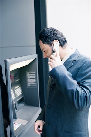 Businessman on Cellphone Using Bank Machine Stock Photo - Rights-Managed, Code: 700-00543518
