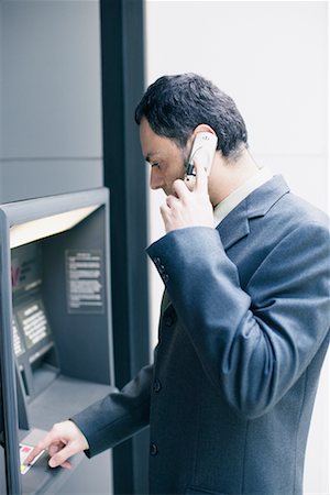 Businessman on Cellphone Using Bank Machine Stock Photo - Rights-Managed, Code: 700-00543519