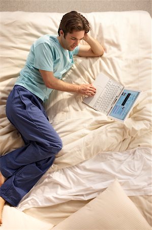 Man Using Laptop on Bed Stock Photo - Rights-Managed, Code: 700-00557373